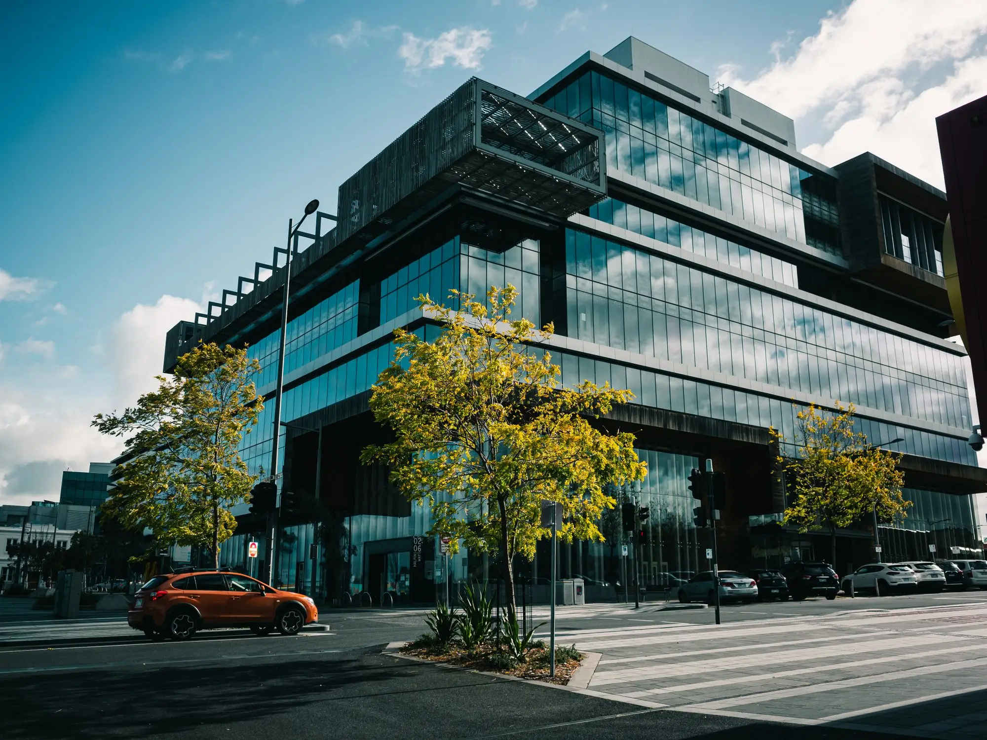 Glass-fronted commercial office building on a street corner in Dandenong, Victoria, under a blue sky