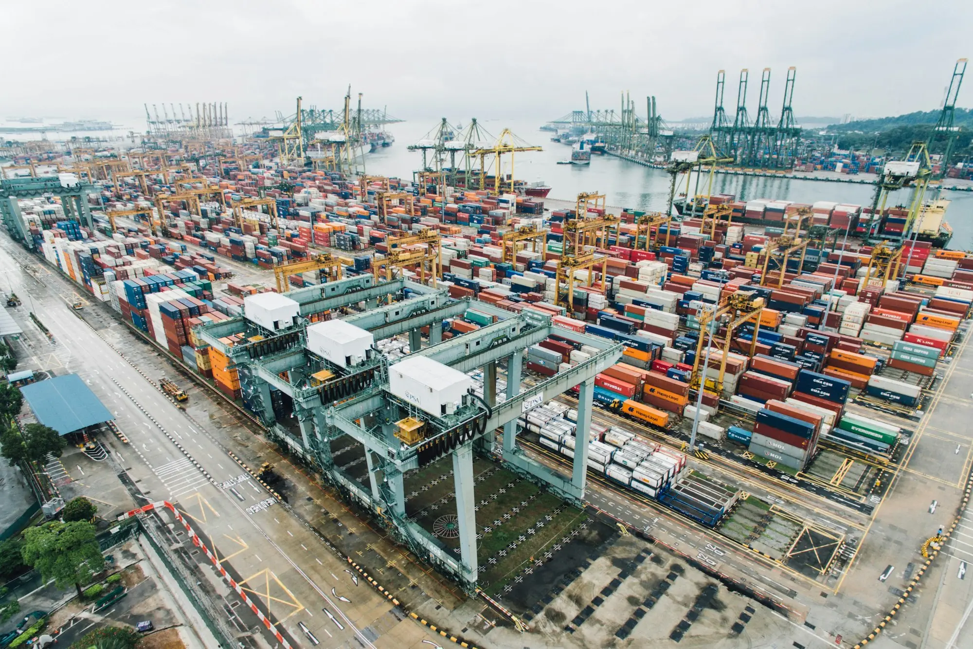 Container port with cranes and stacked shipping containers, where an overseas supplier's order waits for its balance payment before loading